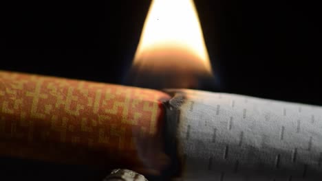 close-up of a cigarette burning with flames erupting from the lit end, capturing the process of combustion and smoke generation in detail