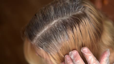 hairdresser is dying hair roots of young woman