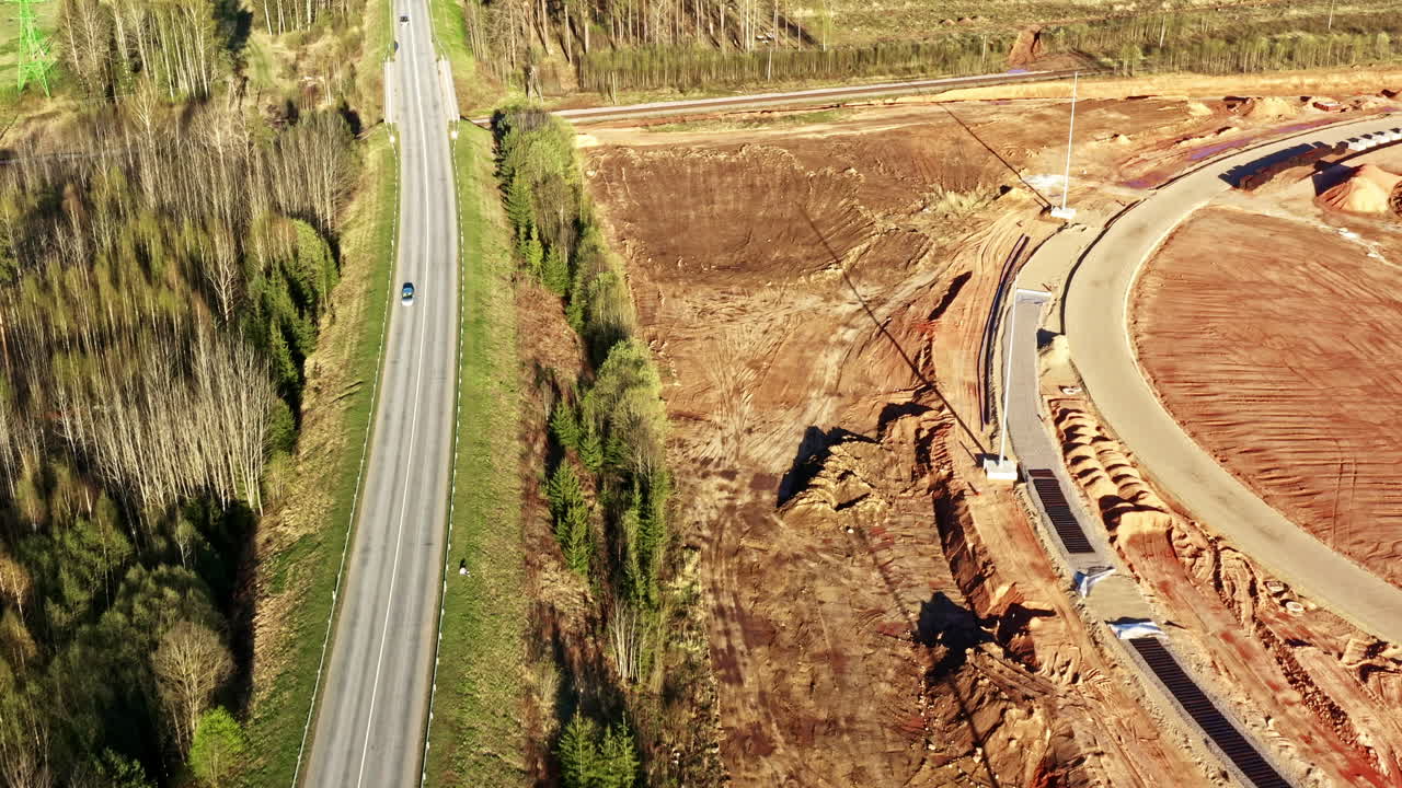 Aerial view of road next to forest and newly cleared construction site