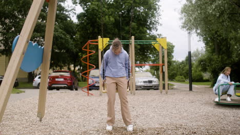 Little-girl-with-down-syndrome-wearing-hoodie-swinging-on-a-swing-in-the-park-on-a-windy-day