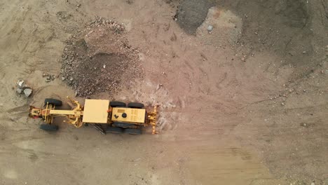 aerial flyover of a construction grader in a dirt lot