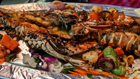 chargrilled lobster served on foil with colorful vegetables and lemon slices. egypt