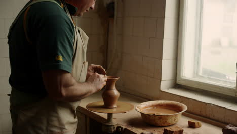 ceramista que fabrica produtos de barro em roda de cerâmica