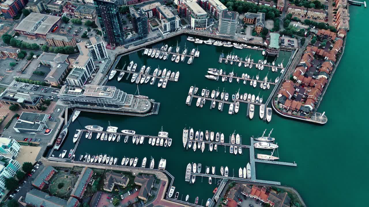 Aerial drone footage of Ocean Village marina in Southampton, showcasing boats, docks, buildings, and waterfront real estate under soft daylight at sunset shot during autumn