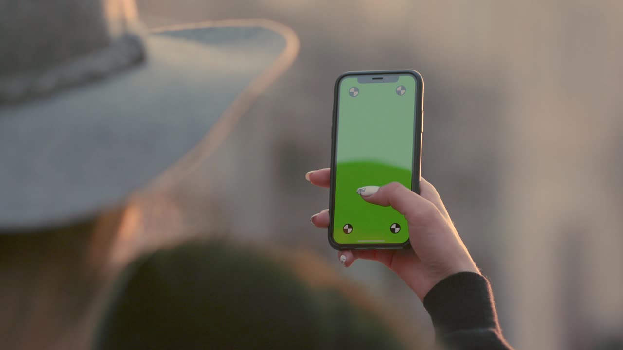 Woman holds up a green screen smartphone against traffic