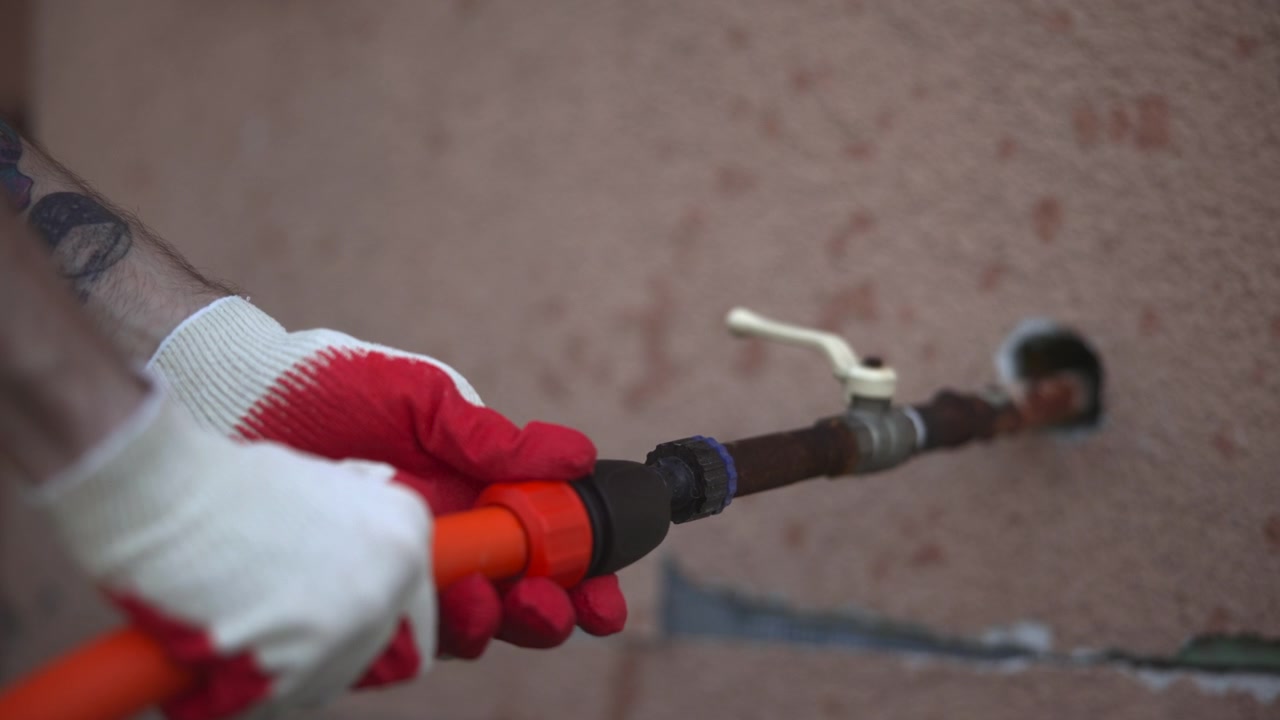 Una vista laterale di un rubinetto dell'acqua esterno a parete con una maniglia bianca su una superficie ruvida e macchiata, mostrato in una luce soffusa e attenuata con messa a fuoco ridotta e aspetto usurato.