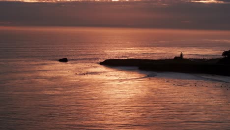 Drone-aerial-view-of-surfers-in-the-beautiful-sunset-in-Santa-Cruz,-California