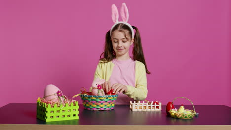 cute smiling toddler decorating a basket with painted easter eggs