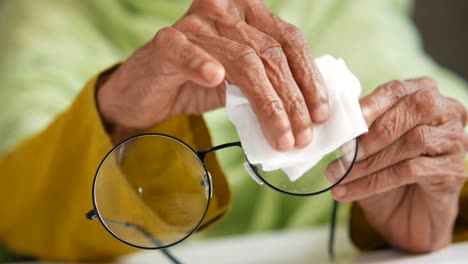 elderly person cleaning eyeglasses