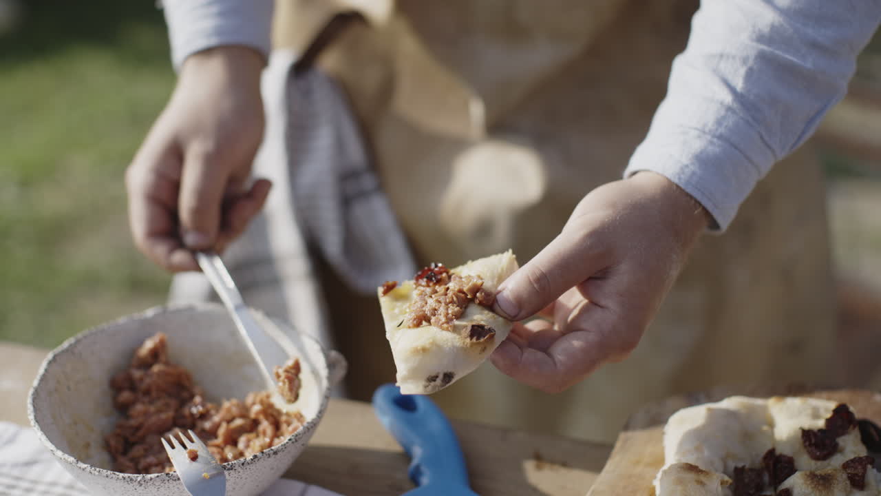 Person preparing a pizza outdoors