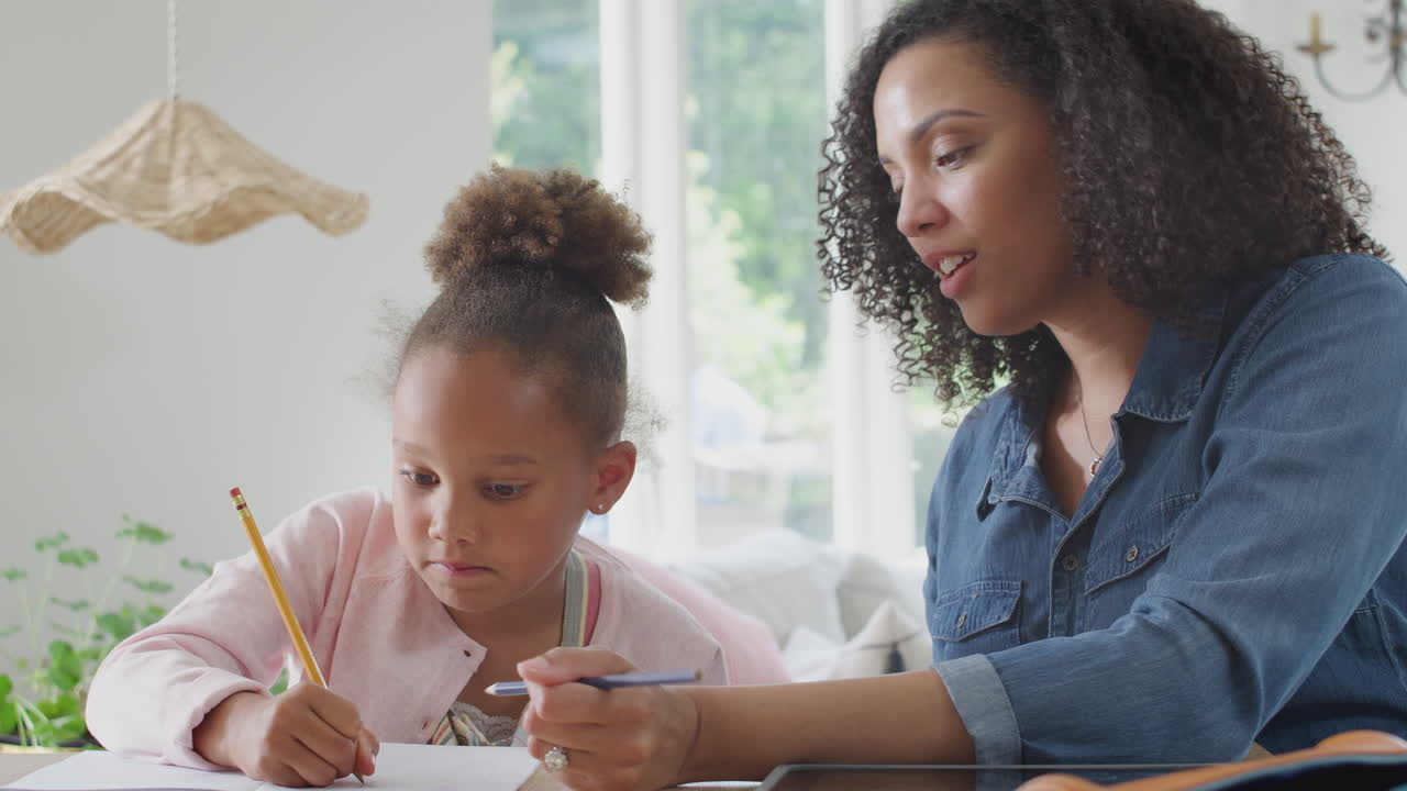 madre ayudando a su hija con la escolarización en casa sentada en la mesa con una tableta digital