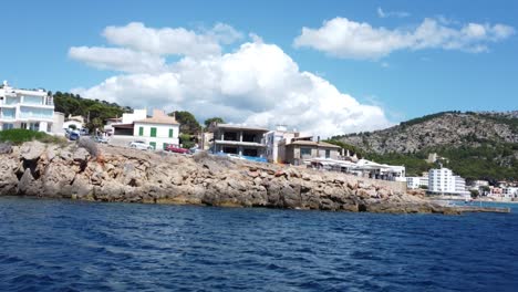 drone flying over blue water close to the shore with buildings then turns right and hovers in mallorca spain beautiful 4k footage