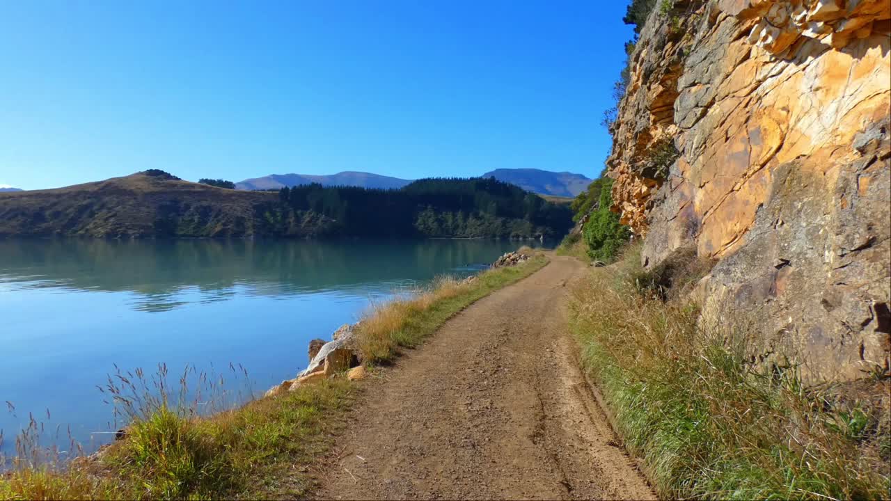 caminar por la vía costera en el puerto junto a una interesante pared de roca volcánica en un hermoso día - vía de la bahía de los gobernadores, península de los bancos