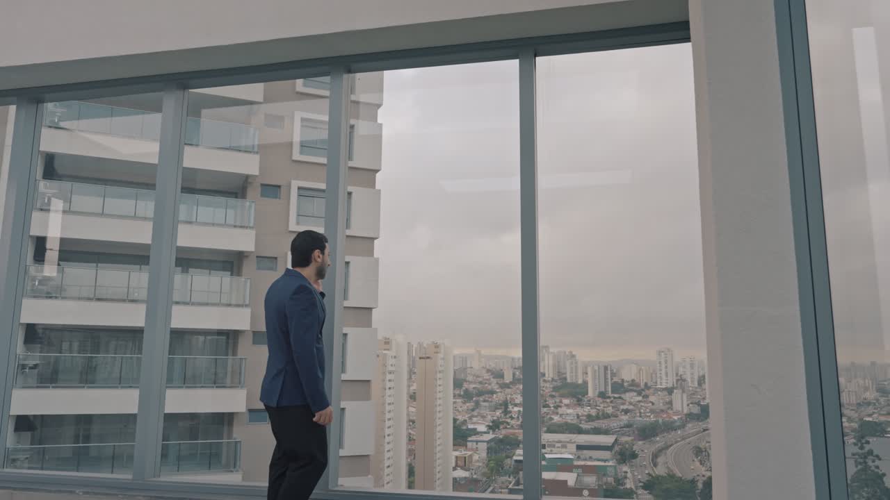 Executive man talking on the phone on the terrace of the building with modern architecture. Zoom in.