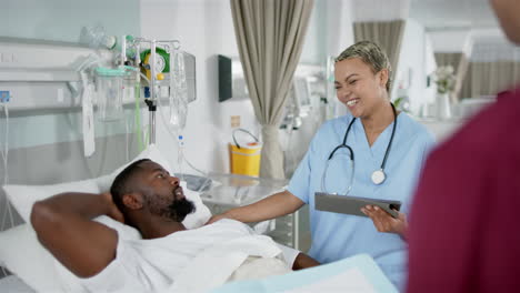 african american female doctor and male patient talking in hospital room, slow motion