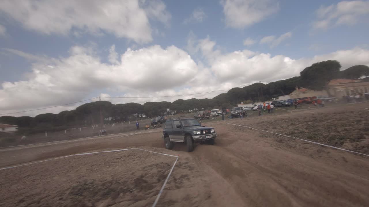 Dynamic FPV flight follows Mitsubishi off road truck in dusty race
