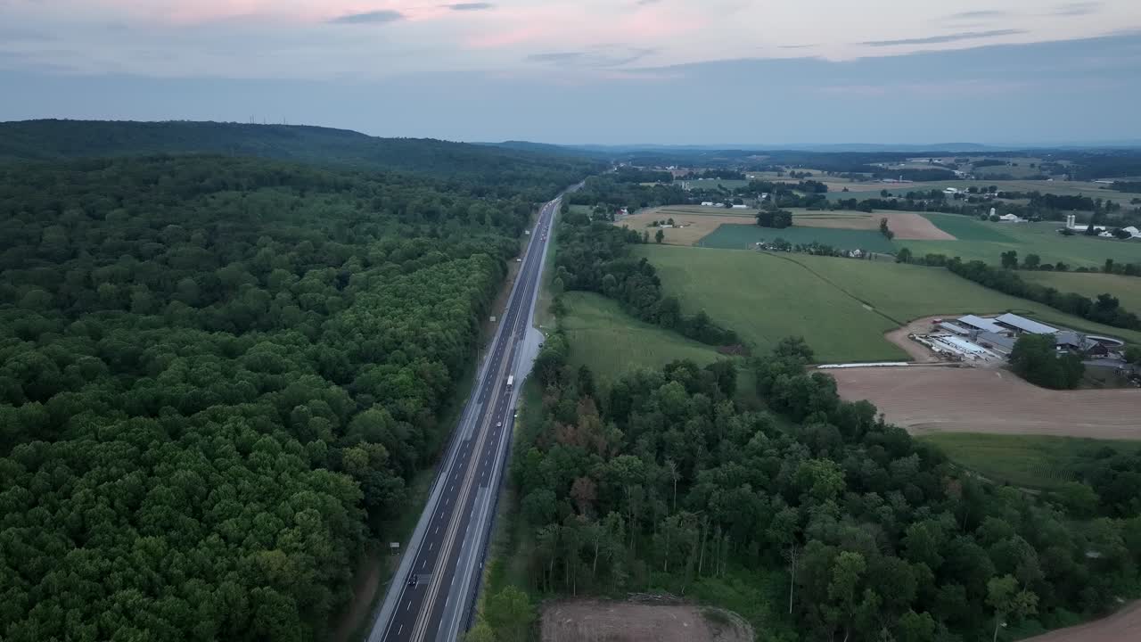 An aerial view of traffic on a highway in the late evening light with the last color of the sunset leaving the sky