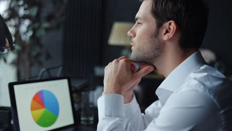 hombre de negocios mirando las estadísticas financieras en la pantalla de su portátil