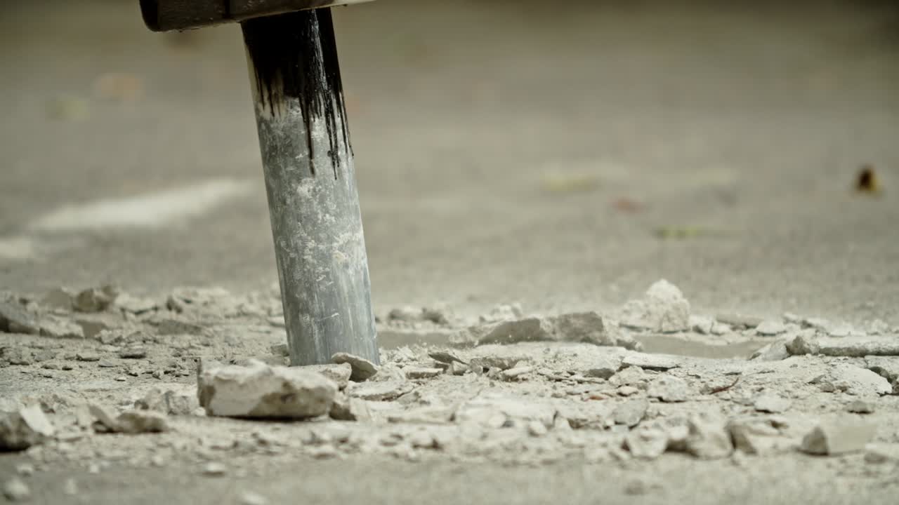 Close-up of excavator hydraulic arm rock breaker working on concrete road