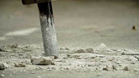 close-up of excavator hydraulic arm rock breaker working on concrete road