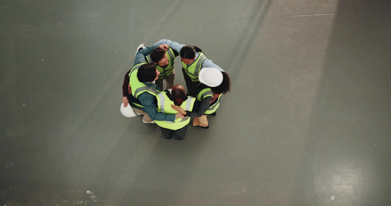 Diverse Team of Construction Workers Huddling Together in Warehouse