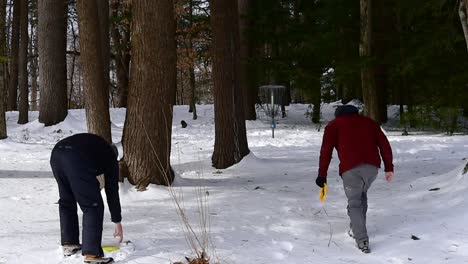 two men playing disc golf in the snow