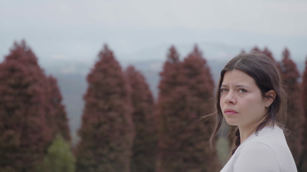 A young woman appears to be searching for her way as she observes the surroundings of the park