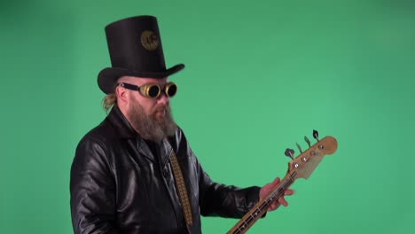 bearded man in long leather coat, an irish style hat and original glasses plays the red guitar. rock musician plays bass guitar in studio on green screen chroma key. slow motion. side view. close up