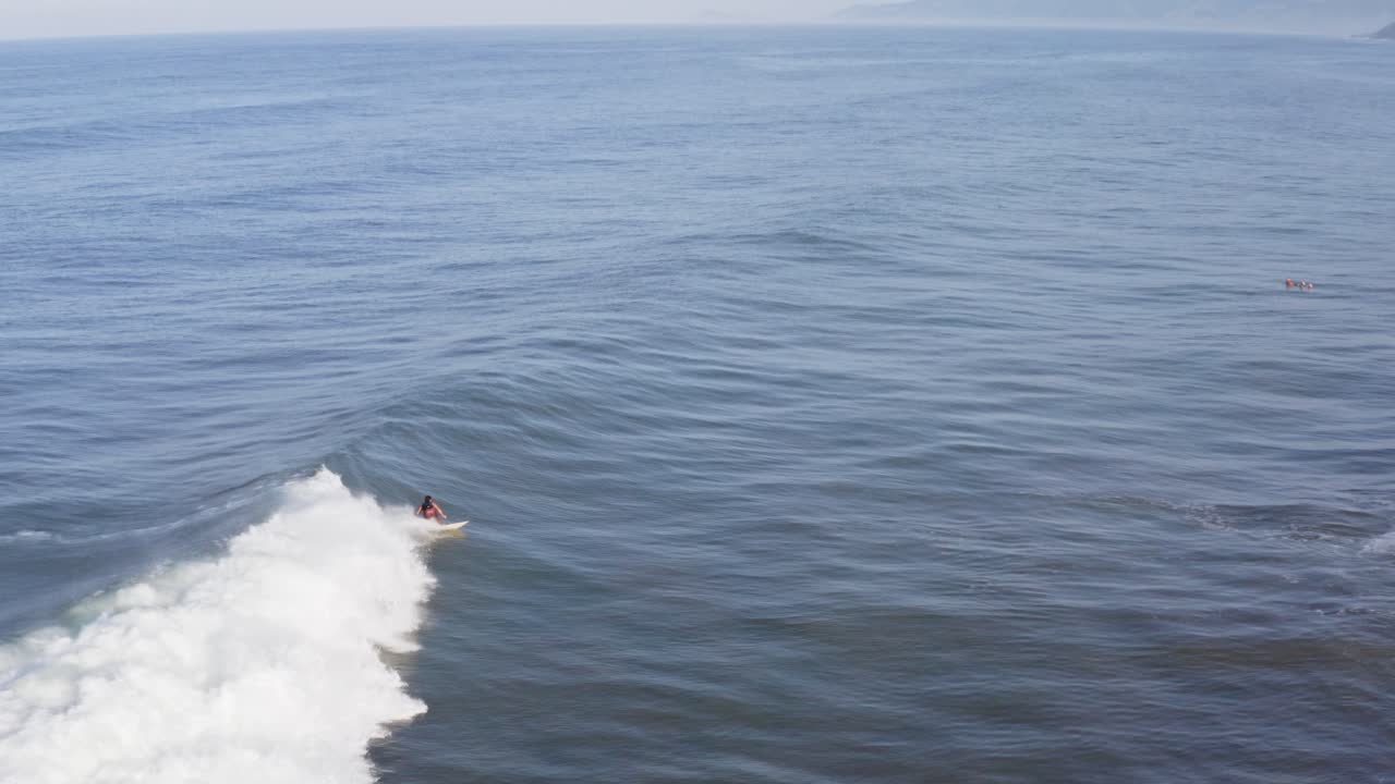 Aereo: surfista che cavalca una lunga e bellissima onda e surfa fino alla spiaggia, vista in inseguimento