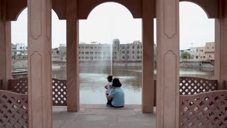 isolated-young-mother-and-cute-toddler-son-enjoying-togetherness-sitting-at-outdoor-at-evening