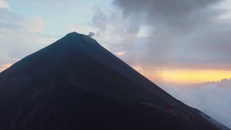 a lot of smoke coming out from a volcano with people watching it on a ridge close by