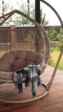 stylish outdoor hanging egg chair with plaid blanket