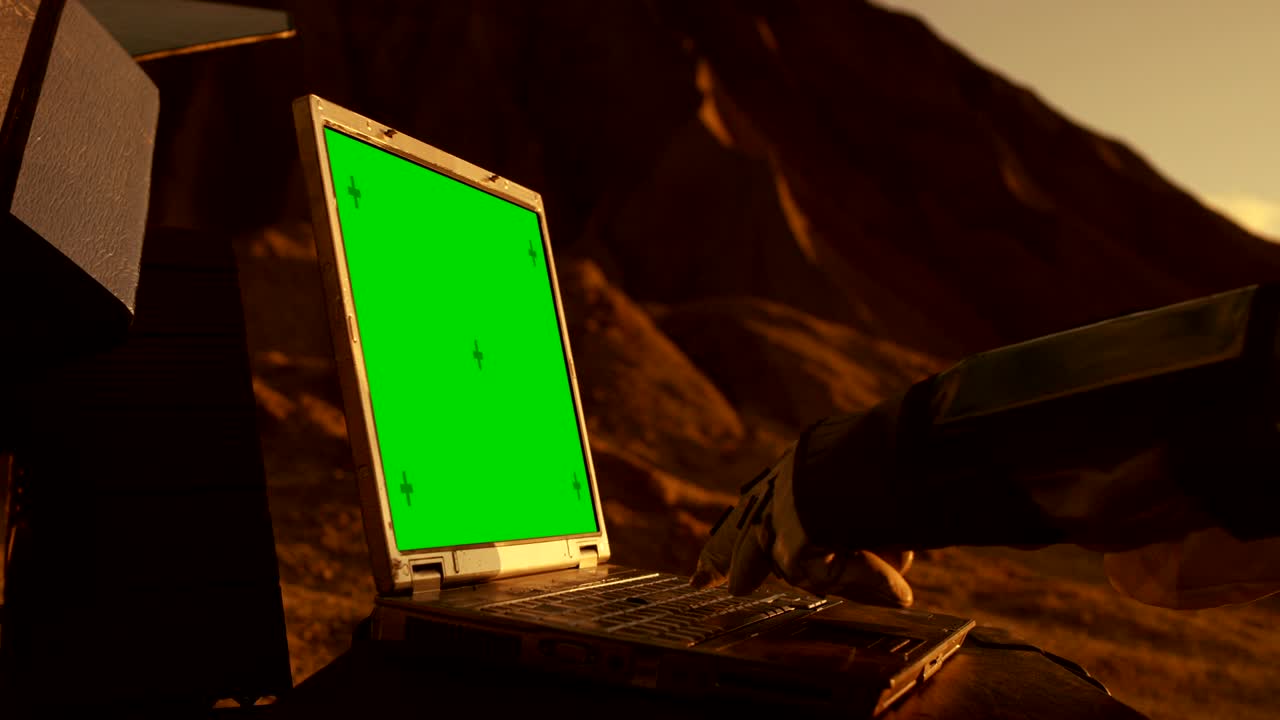 un astronauta en el planeta rojo alienígena o marte trabaja en una maqueta de una computadora portátil de pantalla verde. exploración espacial, búsqueda de mundos habitables y colonización.