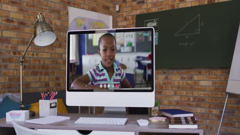 Webcam-view-of-african-american-school-girl-on-video-call-on-computer-on-table-at-school