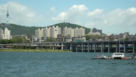 han river near banpo bridge, catamaran and sailing boat floating in dock namsan seoul tower on background on cloudy sunny day no dust, wide-angle, static