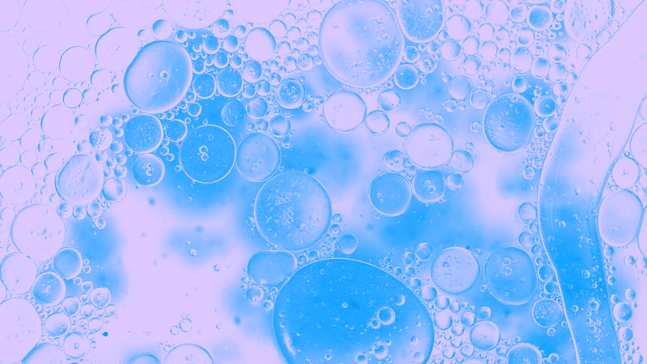 Colorful oil drops floating on water surface, top view. Fantastic abstract background. Bright bubbles moving and spreading. Close up 4k video of weird liquid structures. Scientific chemical experiment