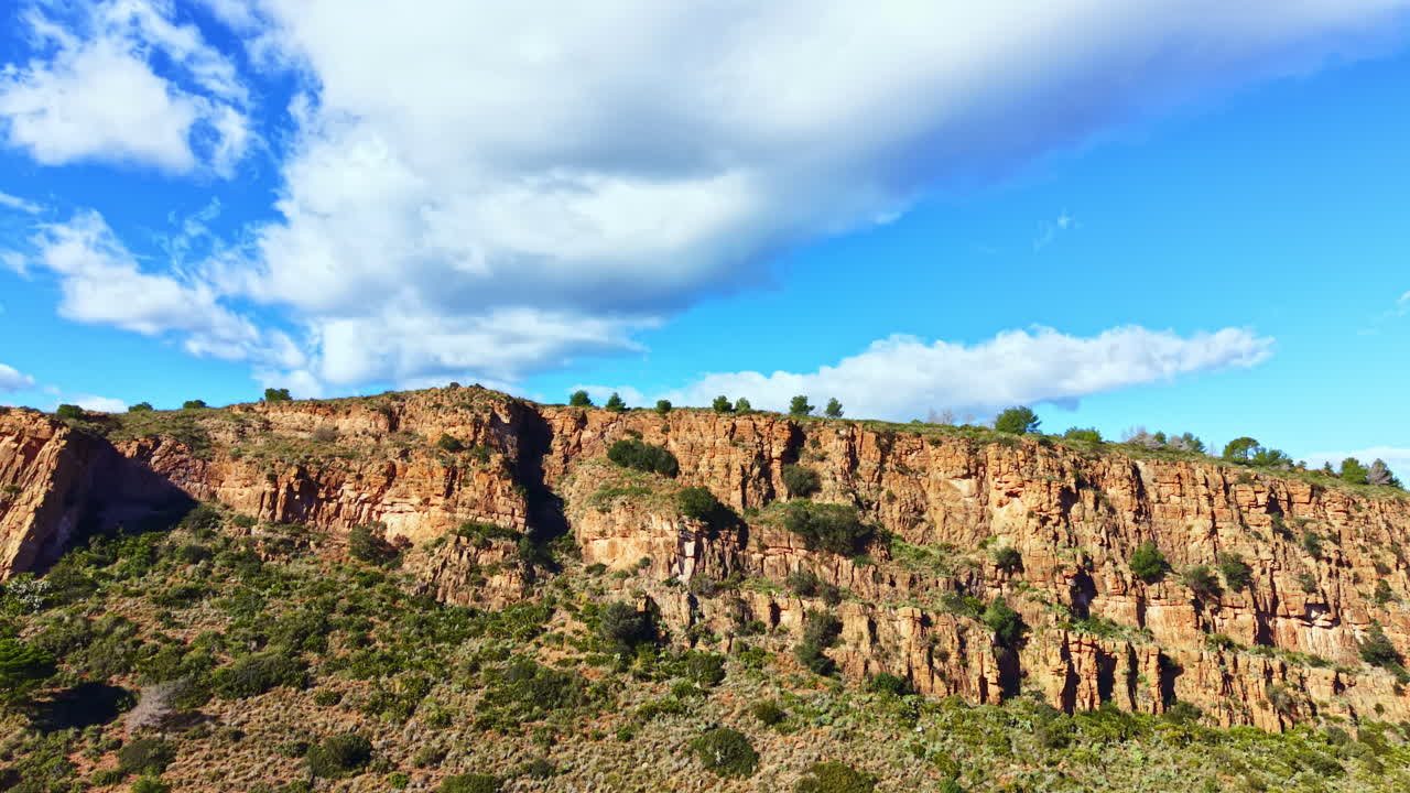 Cielo luminoso sopra scogliere rocciose con vegetazione rada a mezzogiorno in una regione desertica