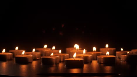 close-up view of person setting burning candles in darkness