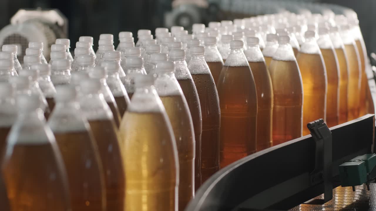 Transportbånd med flasker til juice eller vand på en moderne drikkevarefabrik. Moderne produktion af sød sodavand