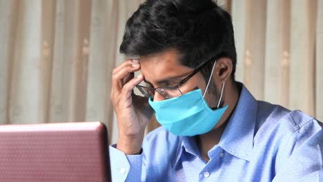 man working on laptop with mask and glasses, stressed