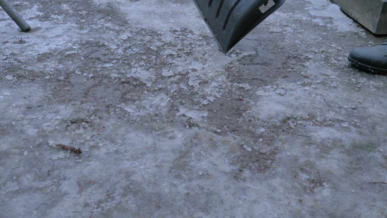 Street cleaner woks with shovel to remove snow and ice from road, ta make it safe for walking