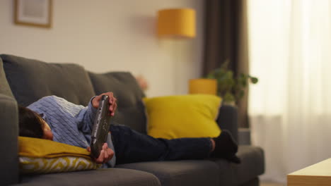 young boy lying on sofa at home playing game or streaming onto handheld gaming device 9