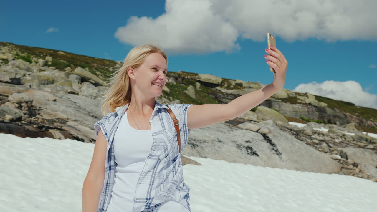 una mujer feliz haciendo selfie en un glaciar en noruega hace calor pero la nieve aún no se ha derretido la mañana
