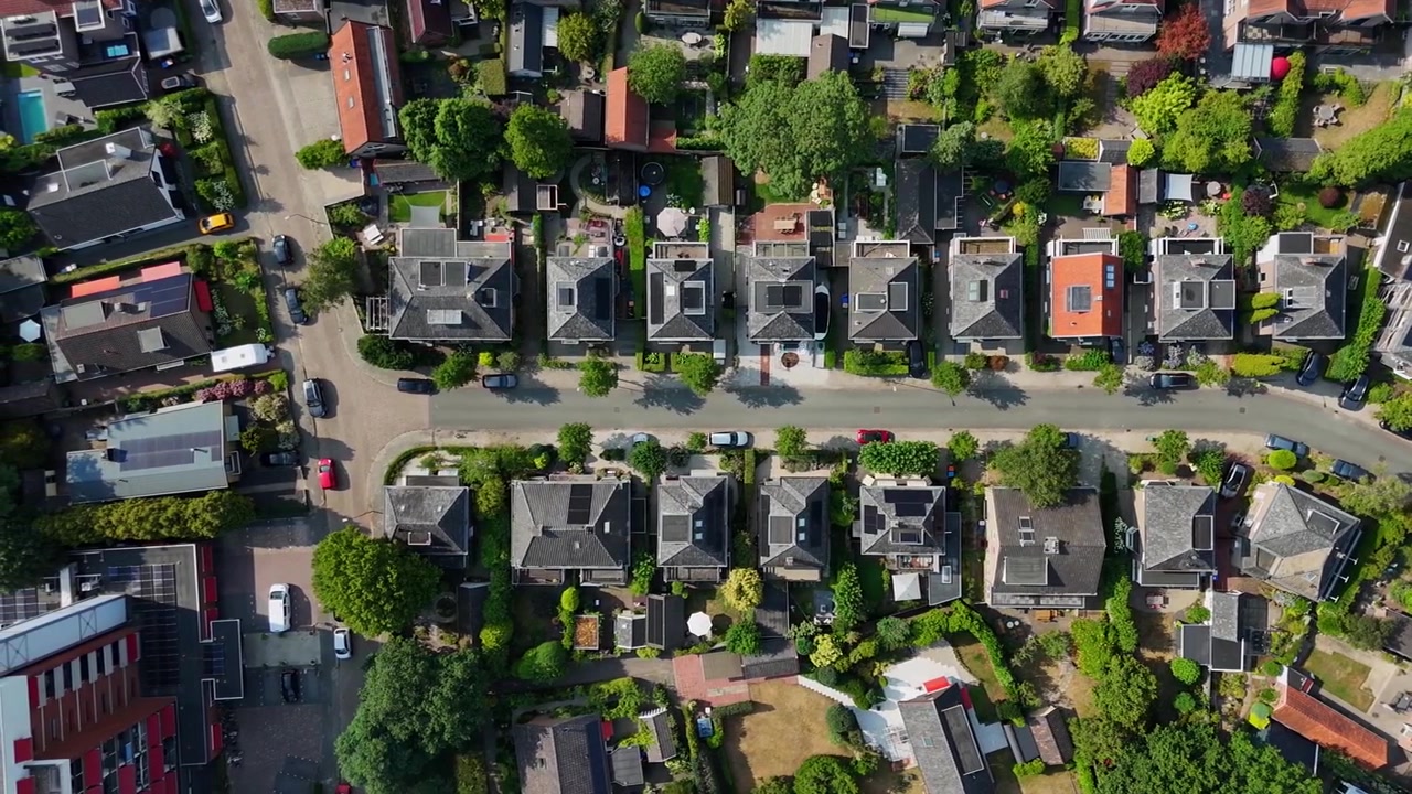 Flygfoto uppifrån över en bostadsgata i Apeldoorn, Nederländerna, med fristående hus, trädgårdar, parkerade bilar, gröna träd och förortsområdeslayout