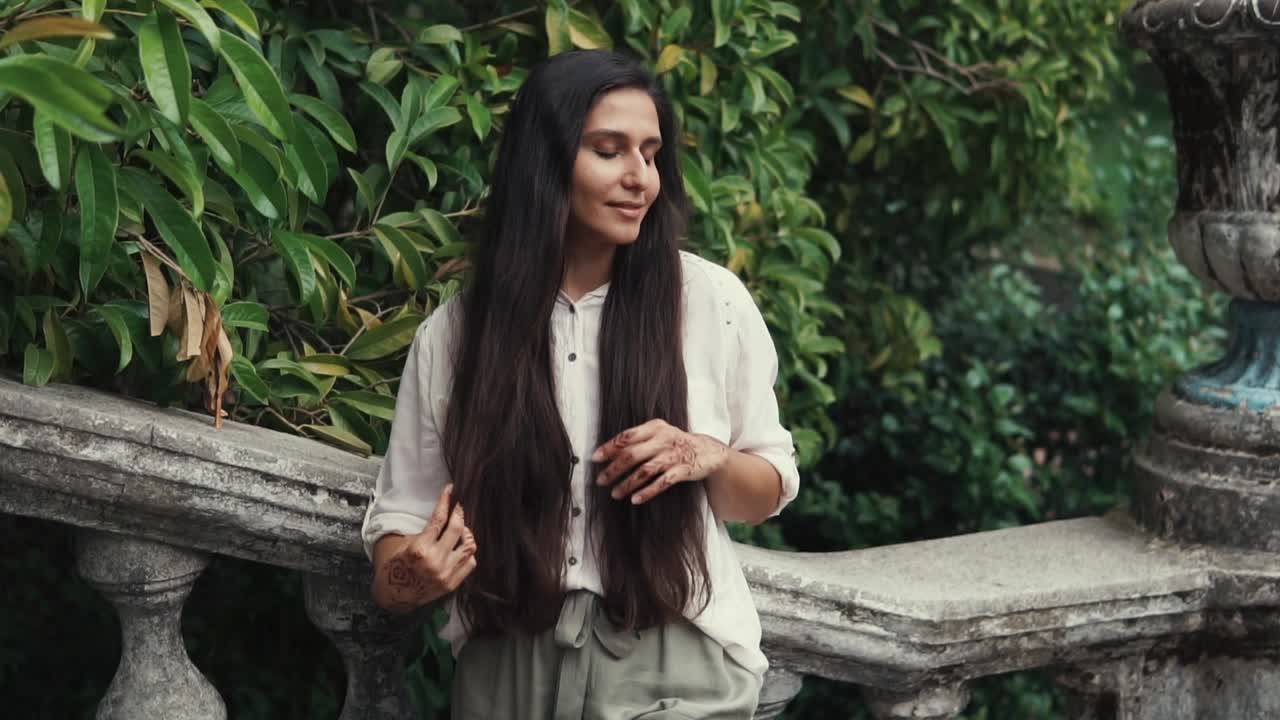 긴 머리카락과 헤나를 가진 정원에 있는 여자