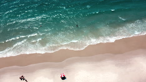 An-awe-inspiring-aerial-view-capturing-the-splendor-of-waves-breaking-on-the-beach,-seen-from-a-majestic-cenital-perspective,-showcasing-the-dynamic-beauty-of-the-coastal-scene