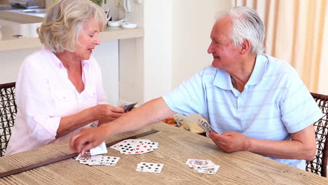 senior couple sitting at table playing cards