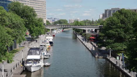 shot of rideau canal next to the senate of canada building on a sunny summer day with several boats in frame - 4k