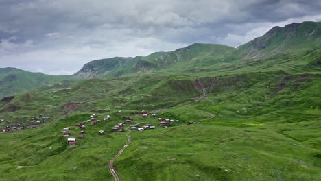 aerial – flying along sloping green hills and small mountain villages