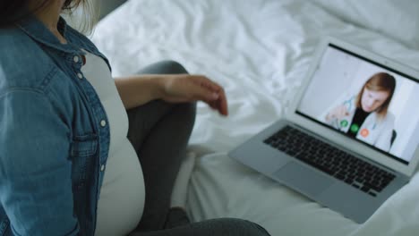 Tilt-down-video-of-pregnant-woman-talking-with-doctor-online.